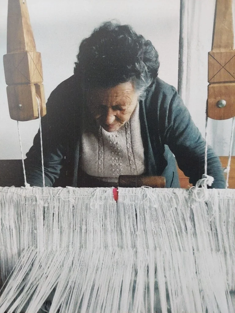 Mulher idosa a tecer num tear tradicional de madeira